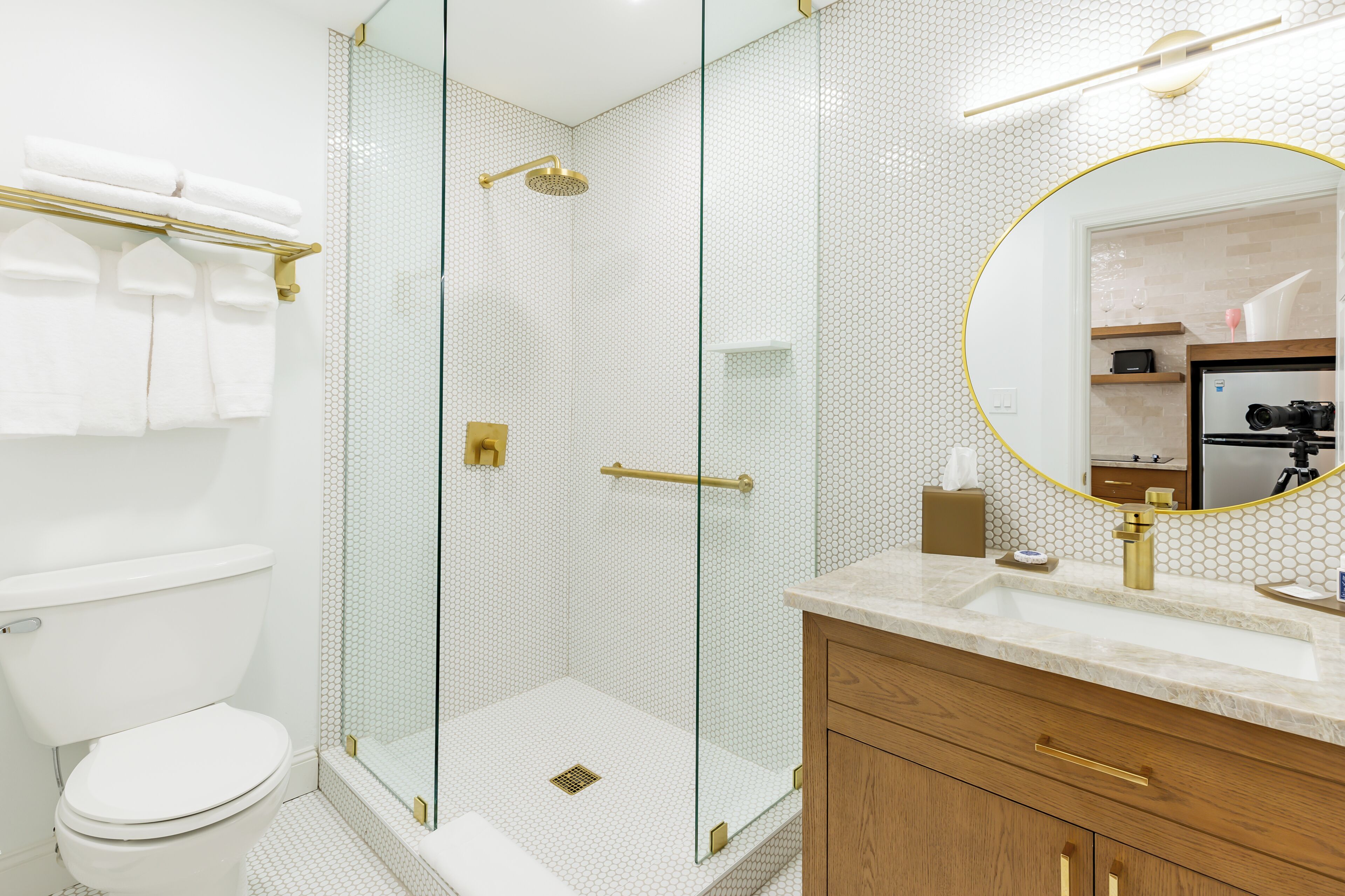 A modern bathroom with a glass-enclosed shower, a toilet, and a vanity with a mirror.