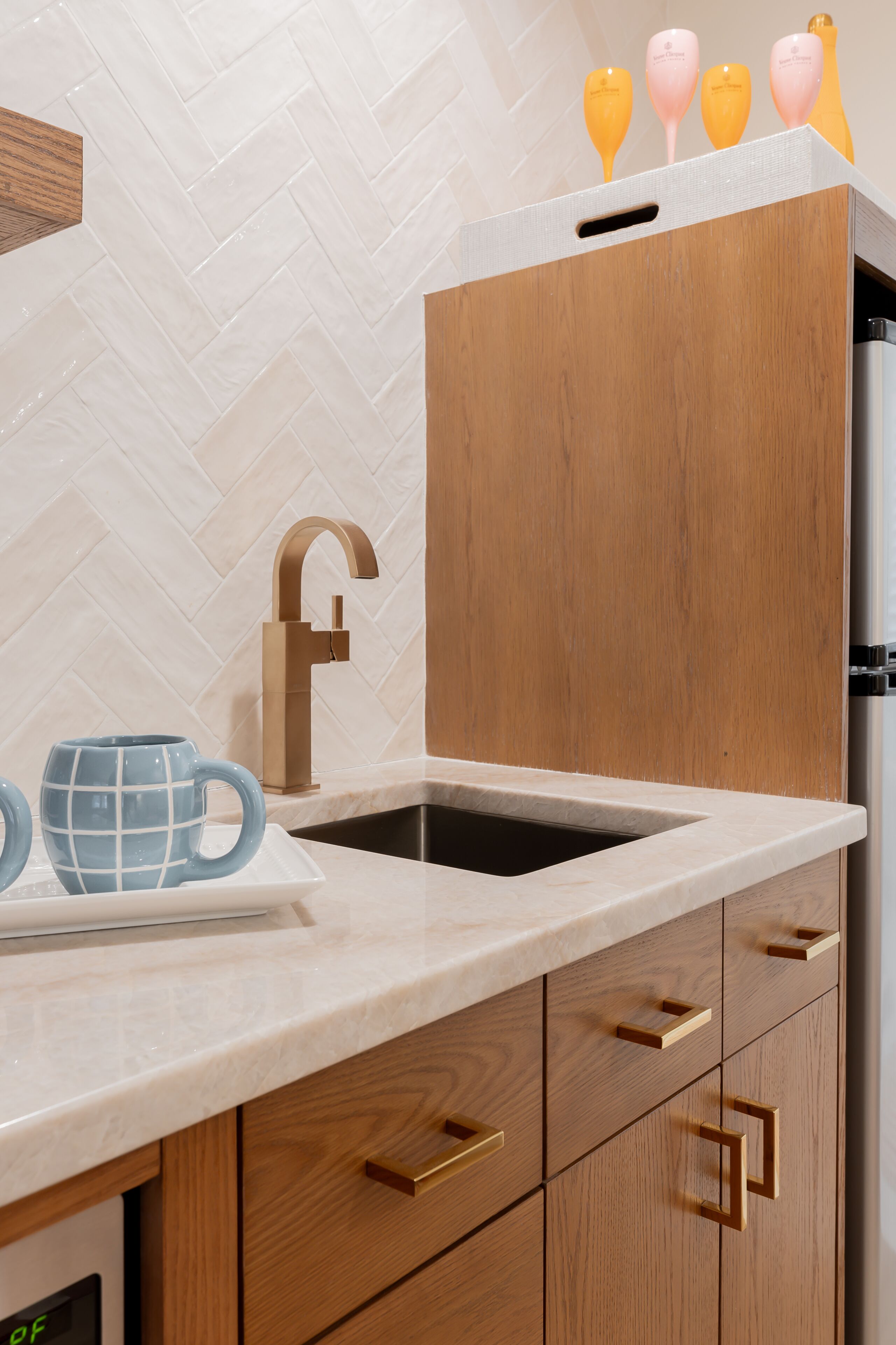 A kitchen with a modern design, featuring a sink, wooden cabinets, and a marble countertop.
