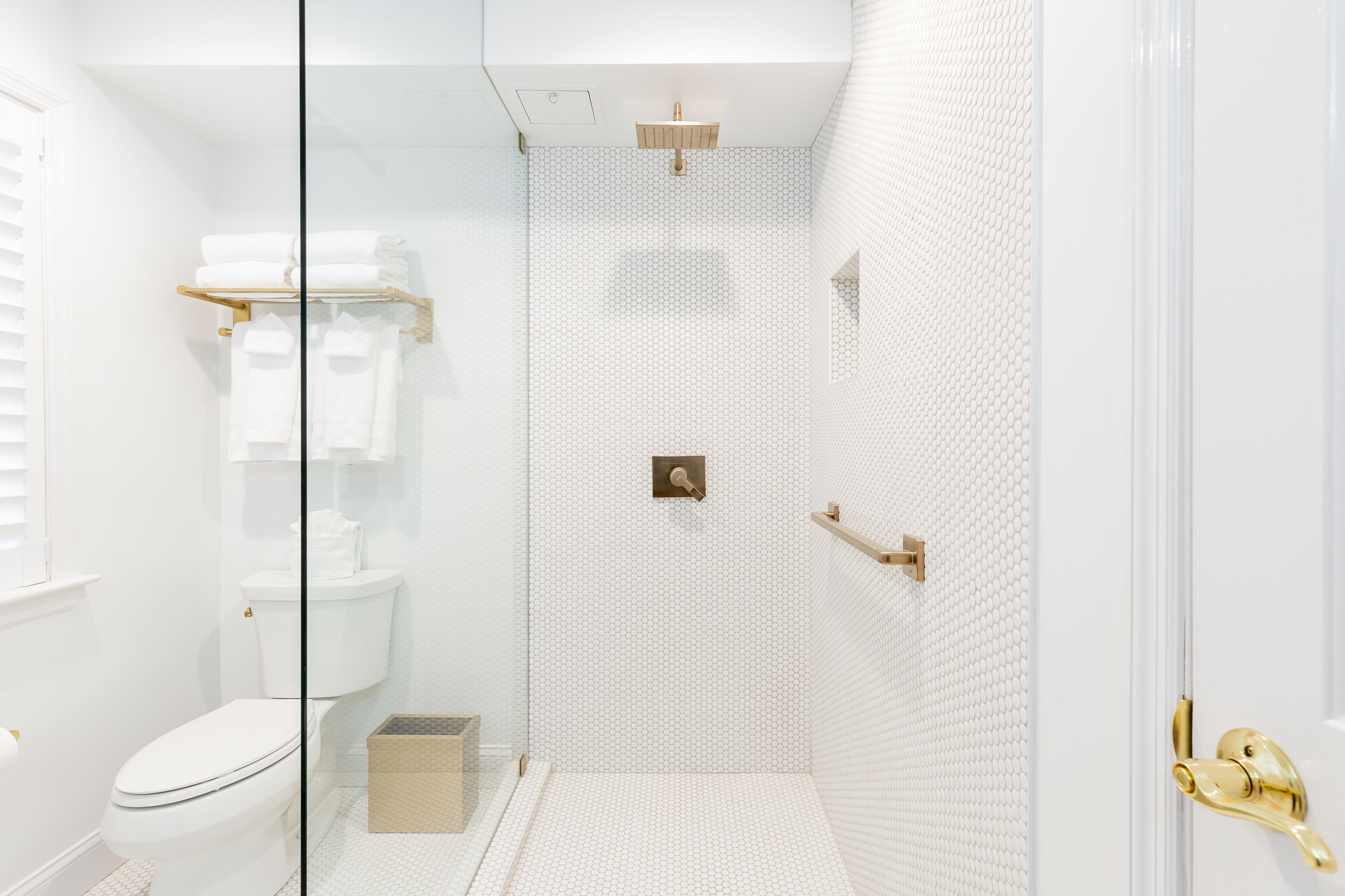 A modern bathroom with a glass shower enclosure, a toilet, and a towel rack.