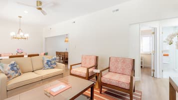 A modern living room with a sofa, armchairs, a coffee table, and a ceiling fan.