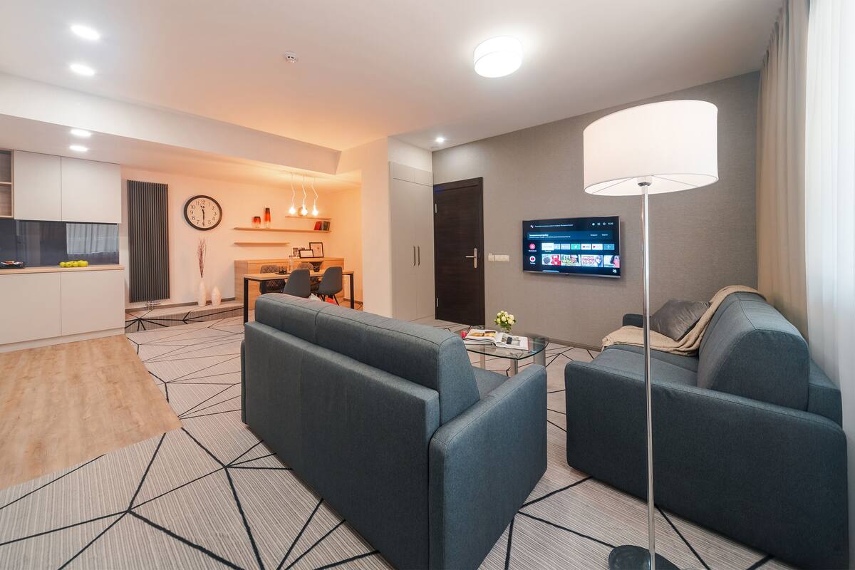 Una sala de estar moderna con un sofá, una mesa de centro y un televisor montado en la pared.
