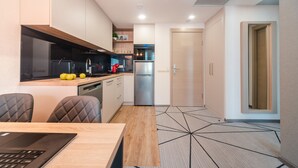 Una cocina moderna con encimera de madera, electrodomésticos de acero inoxidable y un comedor con una computadora portátil sobre la mesa.