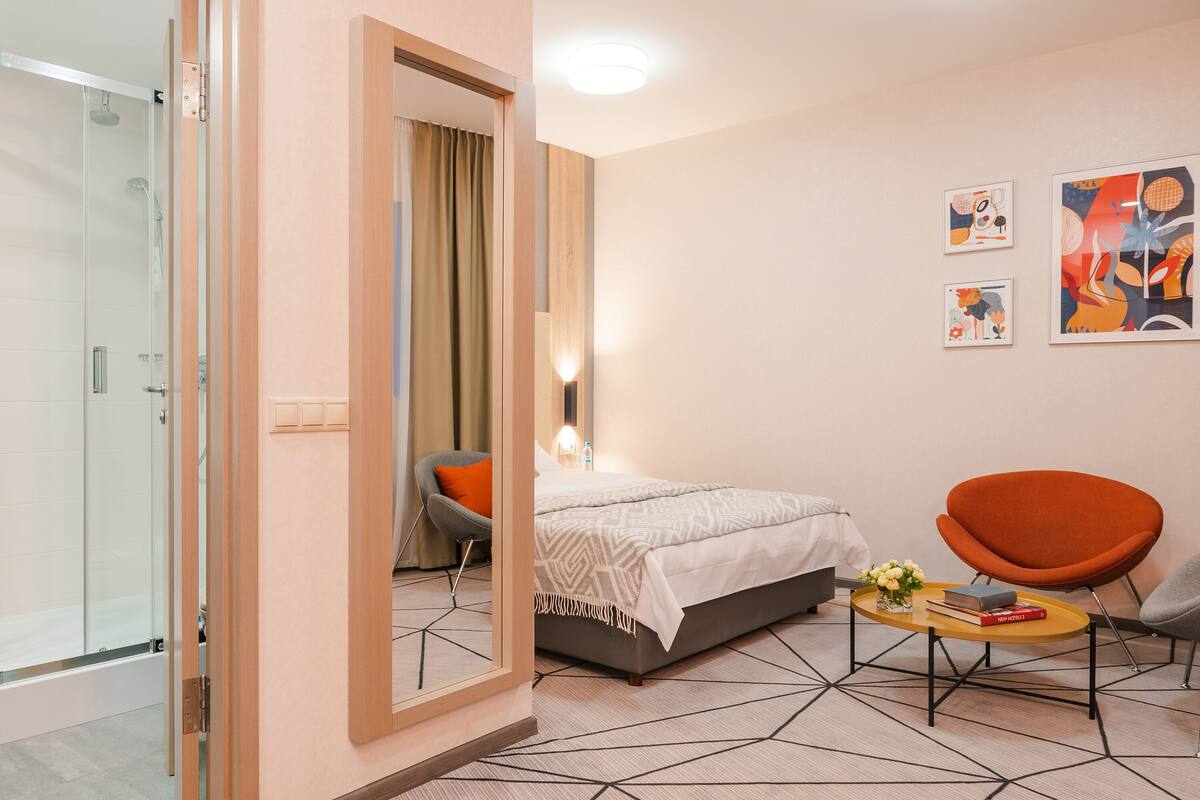 Habitación de hotel moderna con una cama, dos sillones, una mesita de centro y obras de arte en la pared.
