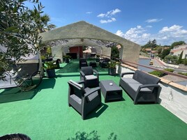 Un área de estar al aire libre con mobiliario de mimbre y césped artificial verde.
