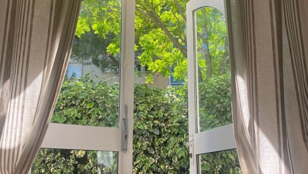 Una habitación con un gran ventanal que da a un espacio exterior con suelo estampado y vegetación.