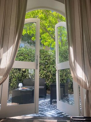 Una habitación con un gran ventanal que da a un espacio exterior con suelo estampado y vegetación.
