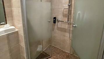 A modern bathroom with a glass-enclosed shower, a sink with a mirror, and a tiled floor.