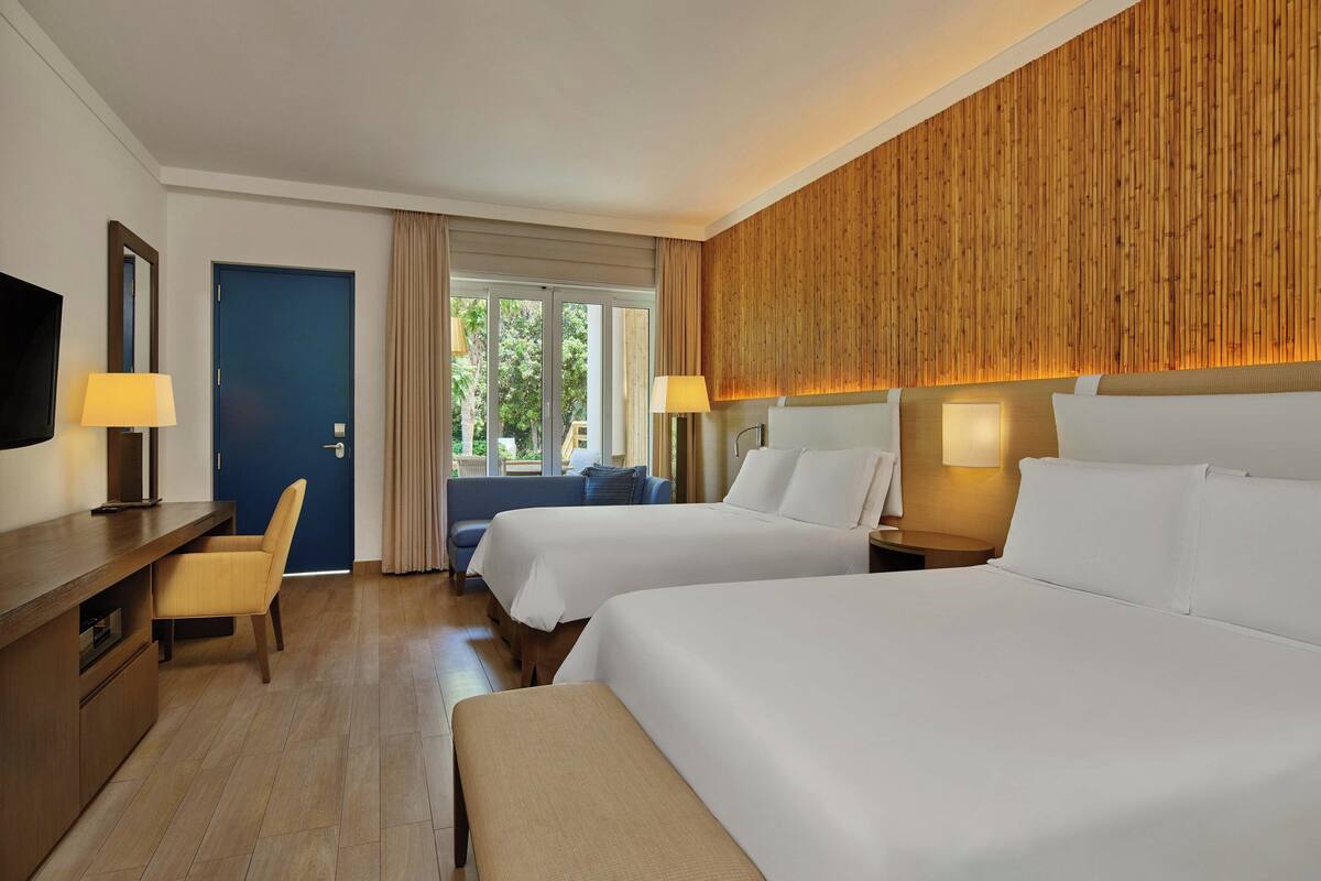 Une chambre d’hôtel avec deux lits, un bureau, une chaise et un téléviseur.