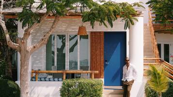 A modern building with a blue door, a staircase, and a garden area with various plants.