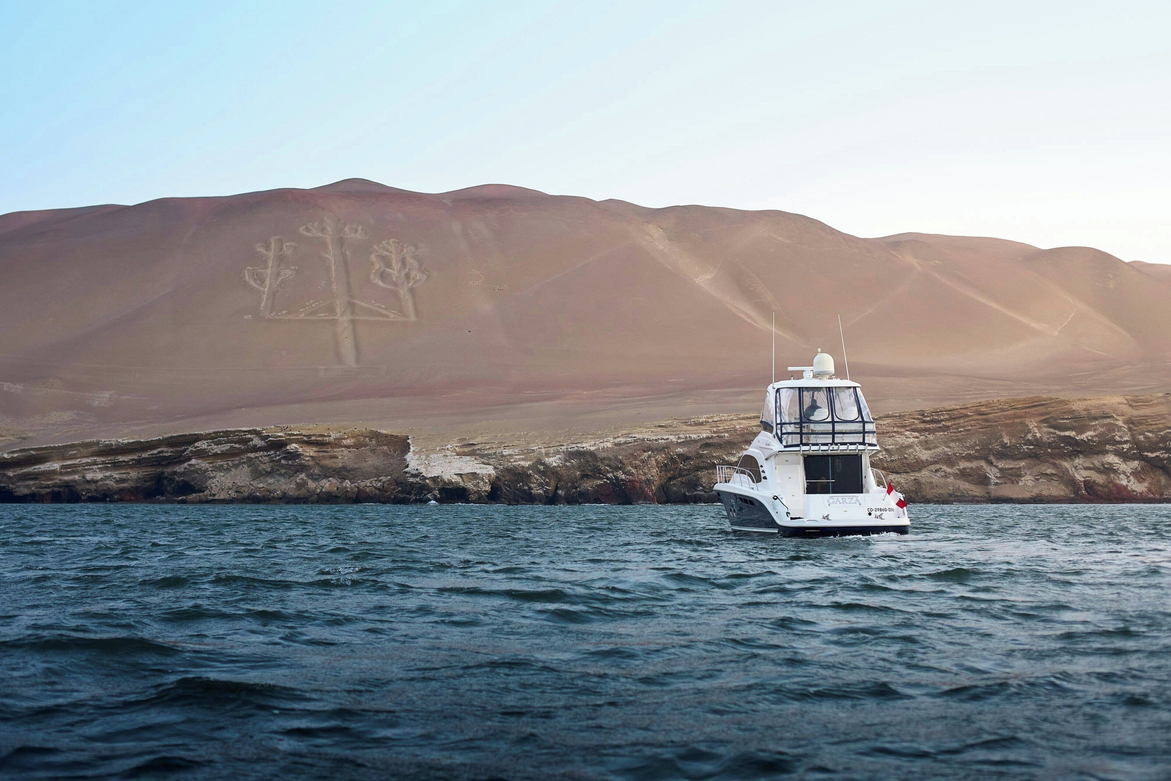 A boat on calm water with a mountainous backdrop.