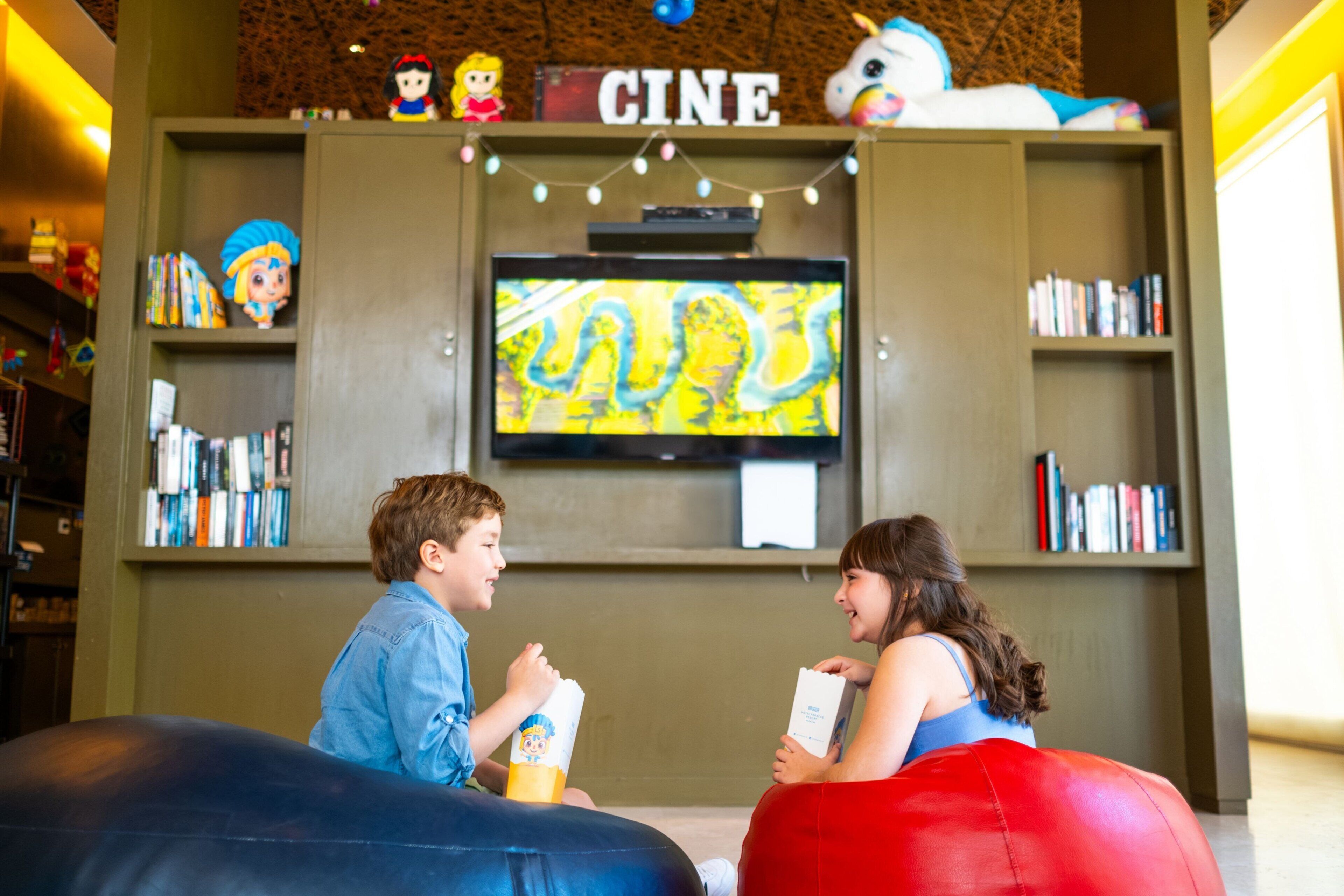 Een kamer met een televisie, boekenplanken en loungestoelen.