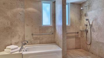 A modern bathroom with a bathtub, shower, and handrails.