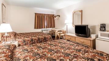 A hotel room with two beds, a desk, a television, a mirror, and a coffee maker.