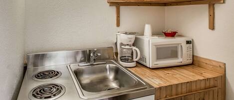 A kitchen with a stainless steel sink, a microwave, and a coffee maker.