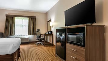 Habitación de hotel con cama, escritorio, silla, televisor, microondas y aire acondicionado.