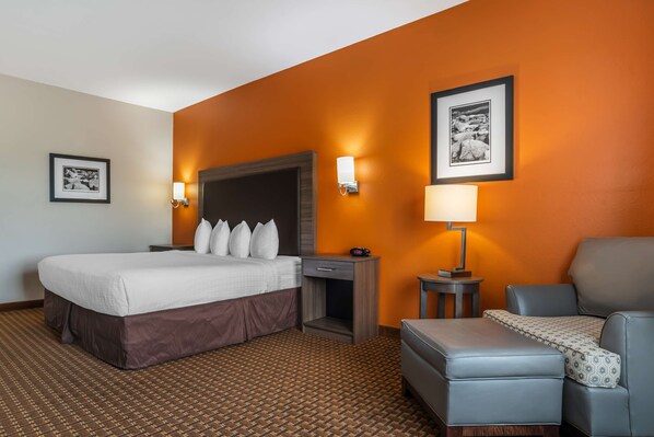 A hotel room with a bed, a desk, a chair, and a sofa.