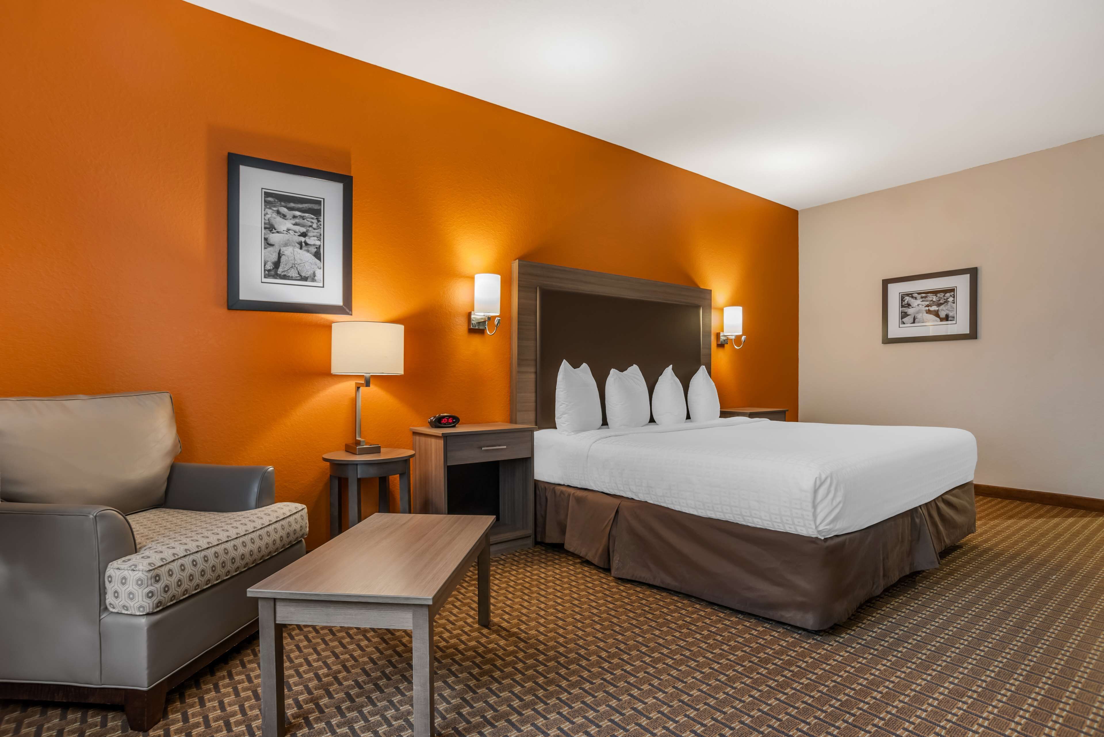 A hotel room with a bed, a sofa, a table, and two wall-mounted lamps.