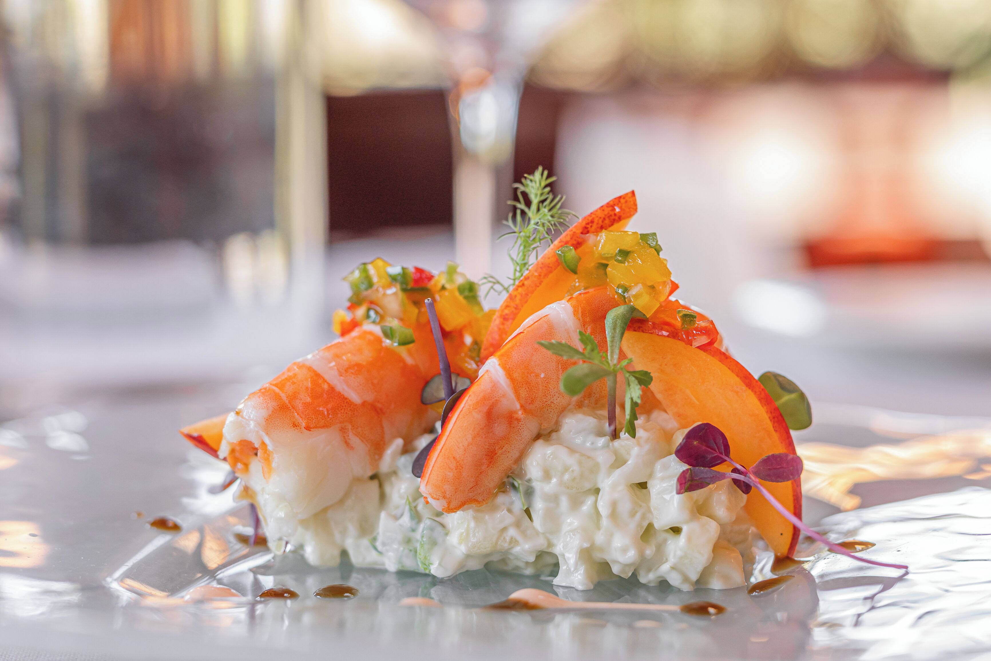 A seafood dish with lobster and vegetables on a glass plate.