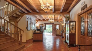 A spacious hallway with wooden beams, a chandelier, a reception desk, and a staircase. - Etxegana Hotel & Spa (Zeanuri)