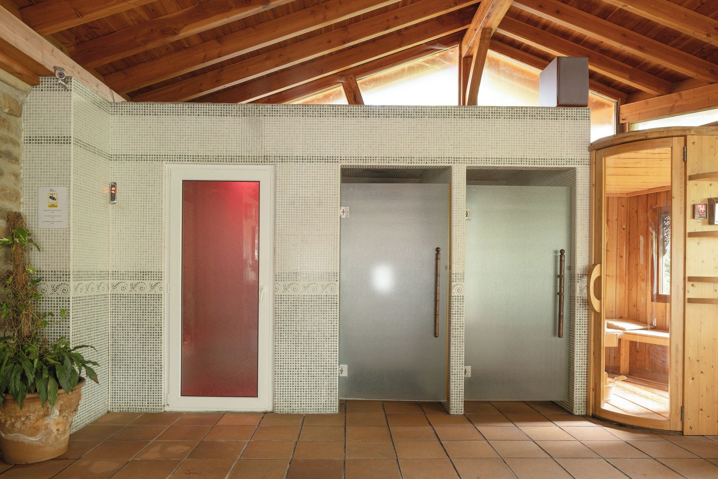 A spa room with a wooden ceiling, tiled walls, and a red door.