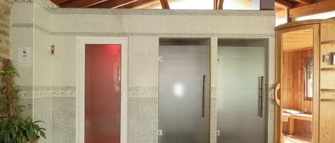 A spa room with a wooden ceiling, tiled walls, and a red door.