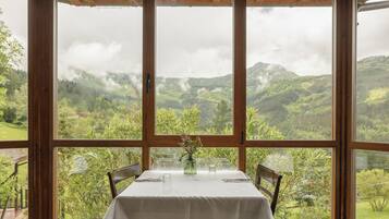 Ein Essbereich mit Tisch für zwei Personen, mit Blick auf ein üppiges Tal und ferne Berge.