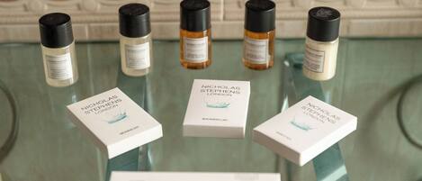 A glass display table with five bottles of Nicholas Stephens London products and their boxes.