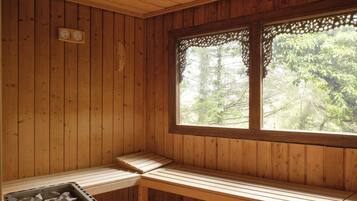 A wooden sauna with benches and a window with lace trim.