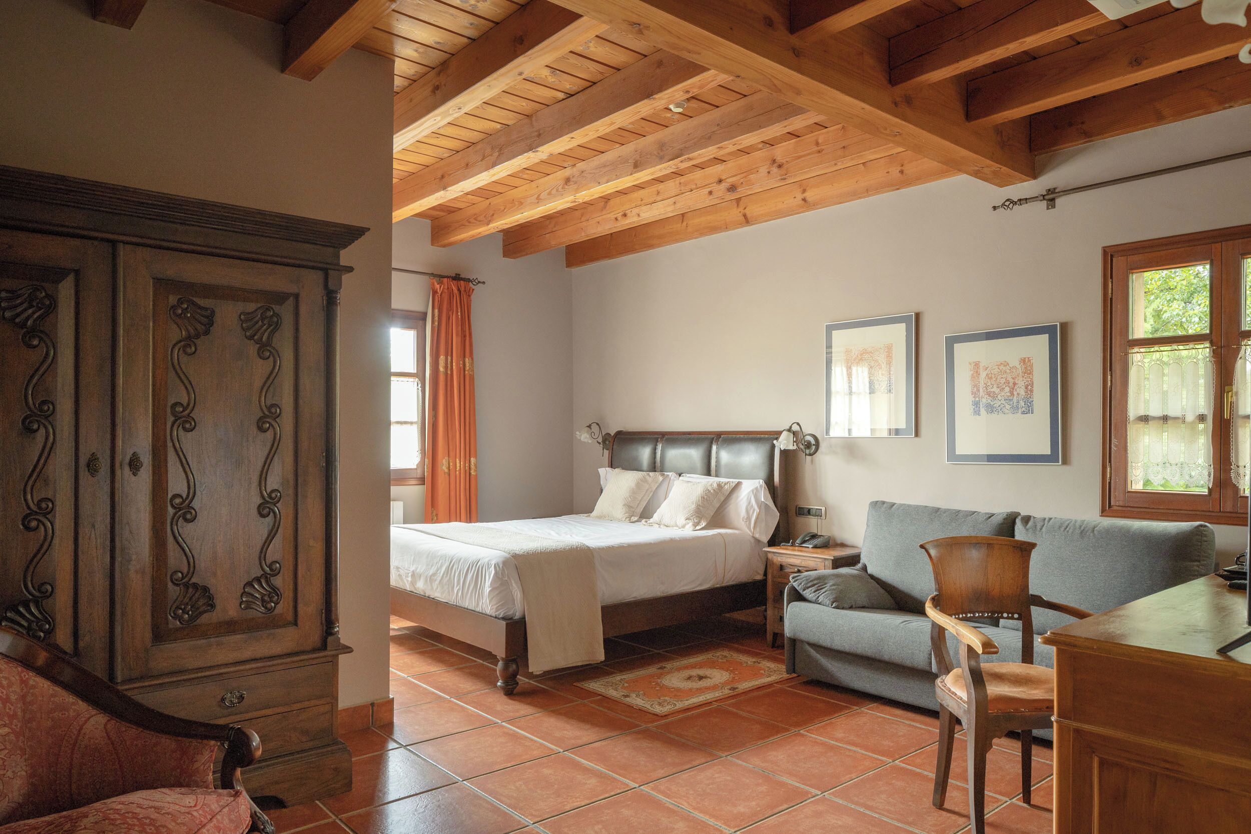 Un dormitorio con cama, armario de madera, mesita de noche, sofá y escritorio.