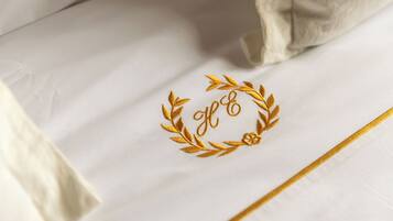 Tejido blanco con un monograma bordado en oro y una corona de laurel.