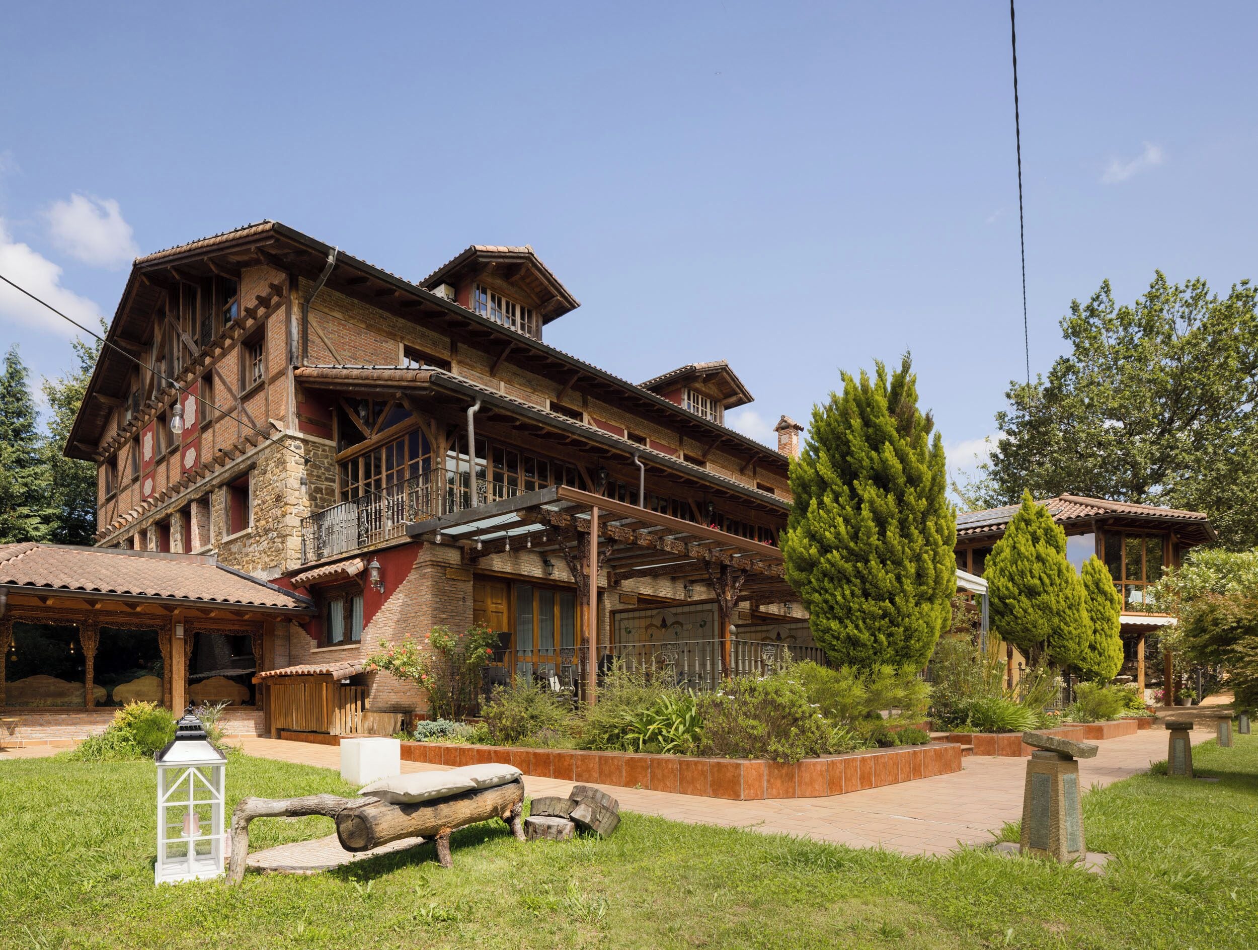 A traditional chalet with a wooden facade, multiple balconies, and a landscaped garden with a stone lantern and wooden benches.