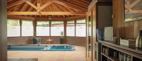 A covered outdoor area with a pool, wooden ceiling, and a bar area with a tea sign.