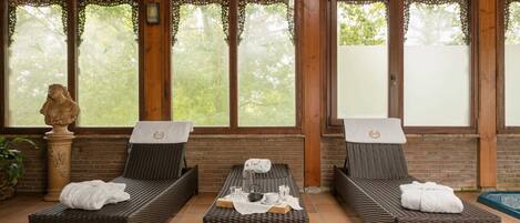 Una habitación con dos sillones de mimbre, una mesita con una toalla y una estatua.