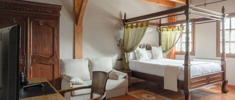 Une chambre à coucher de style traditionnel, avec un lit à baldaquin, une armoire en bois, un canapé et une table.