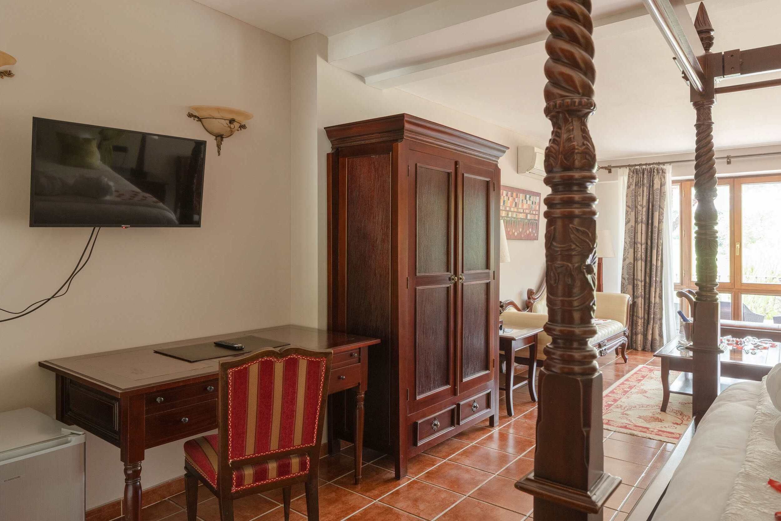 Una habitación con una cama, un escritorio, un televisor, un armario y una silla.