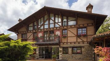A traditional chalet-style building with a wooden facade, large windows, and a balcony with flower boxes.