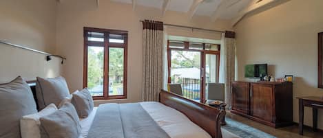Un dormitorio con cama, sofá, televisión y vistas al exterior.