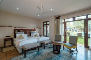 Une chambre d’hôtel comprenant un lit, deux tables de chevet, une chaise, une petite table et une vue sur l’extérieur grâce à une grande fenêtre.