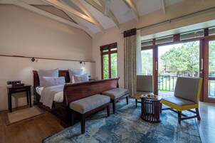 Habitación de hotel con cama, sofá, silla, una mesita con pasteles y vistas al exterior.