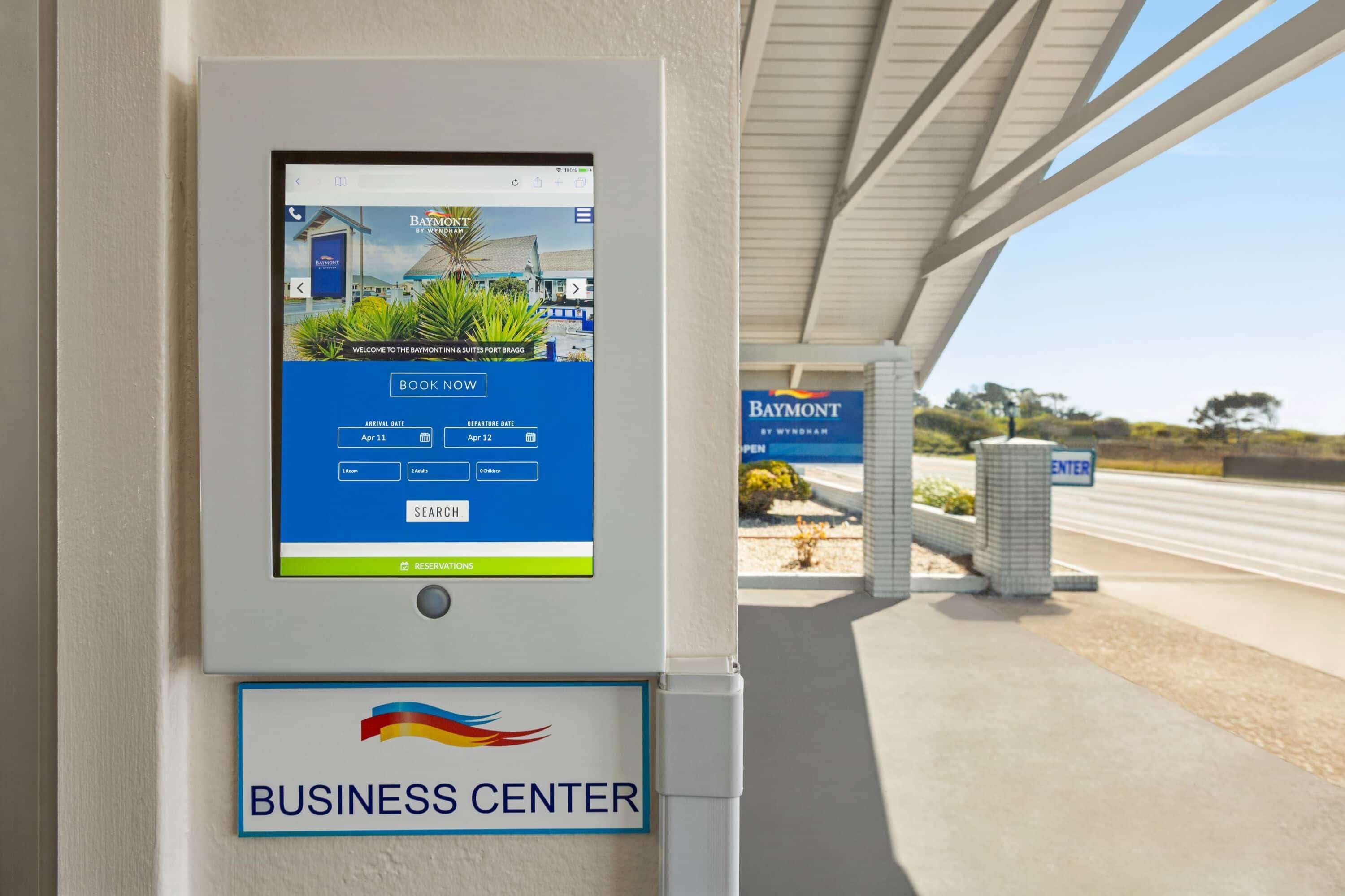 A digital kiosk with a booking interface for Baymont by Wyndham, located at the business center entrance.