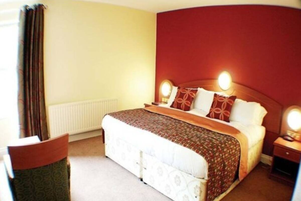 A hotel room with a bed, bedside tables, a chair, and a radiator.