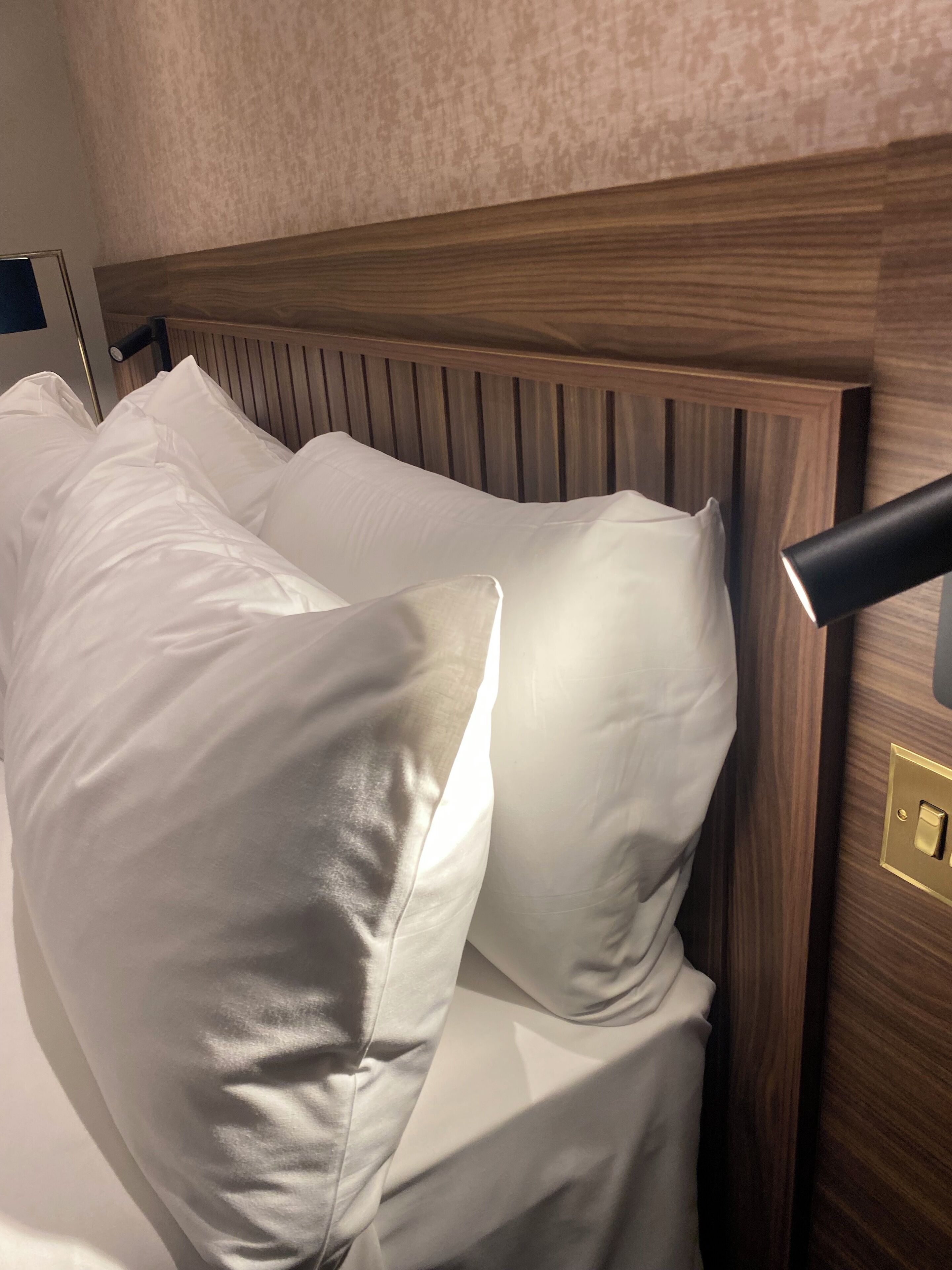 Una cama con sábanas blancas y cabecera de madera.