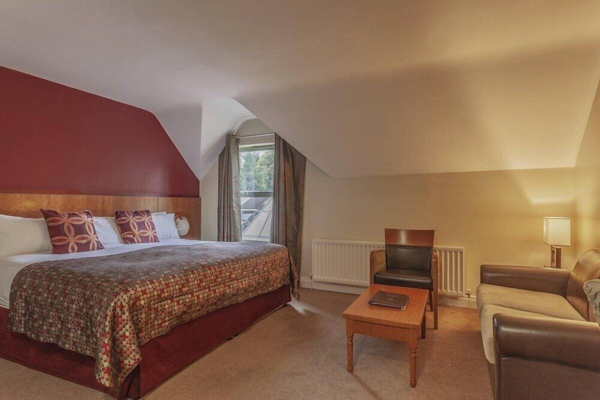 A bedroom with a bed, a chair, a table, and a window.