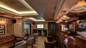 Un área de bar con suelo de madera, taburetes y lámparas colgantes.