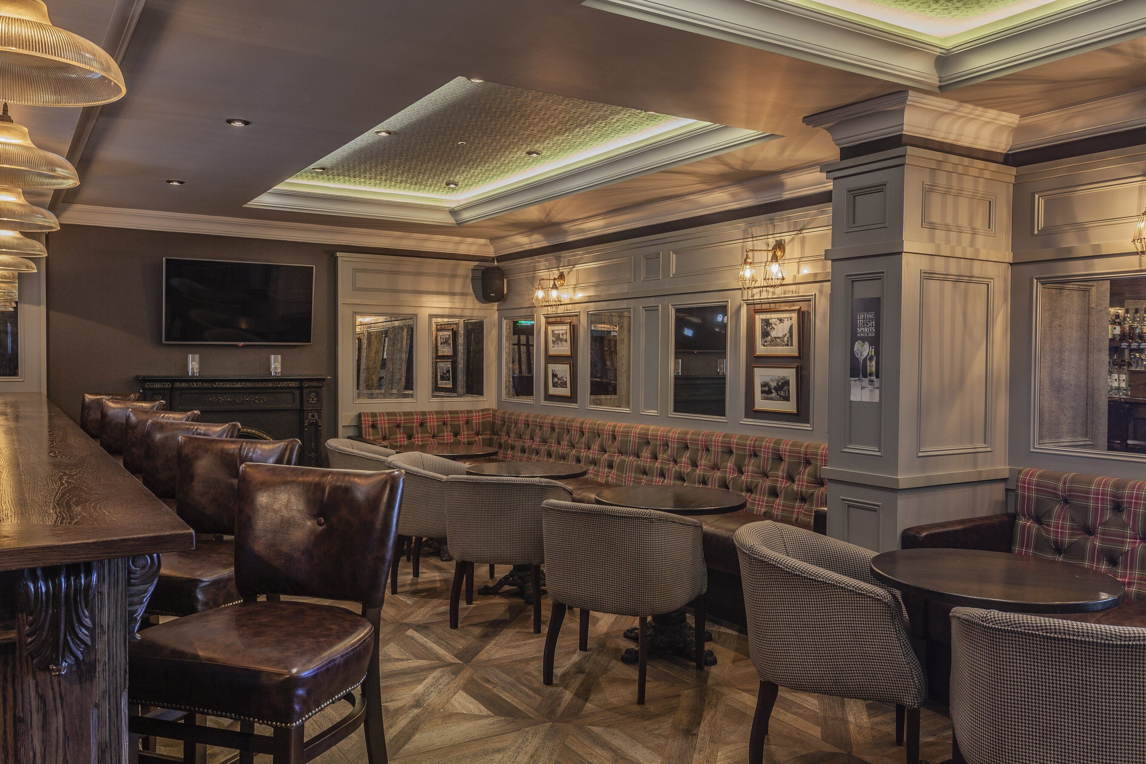 A bar area with leather chairs, a long counter, and a television mounted on the wall.
