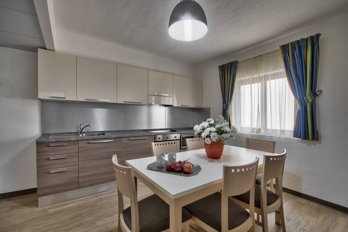 Une cuisine moderne avec des meubles en bois, un plan de travail blanc et un coin repas comprenant une table et des chaises.