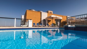 Una piscina con sillones de descanso y un edificio de diseño moderno.