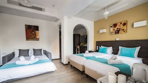 Habitación de hotel con dos camas, una kitchenette y un baño visible a través de un arco.