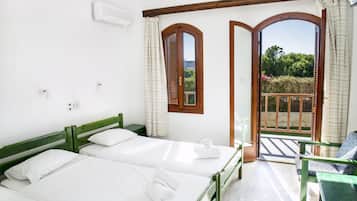 Quarto de hotel com duas camas, varanda com vista e janela emoldurada por madeira.