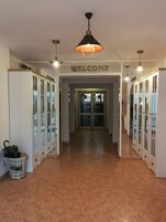A hotel lobby with a 'WELCOME' sign, glass doors, and a tiled floor.
